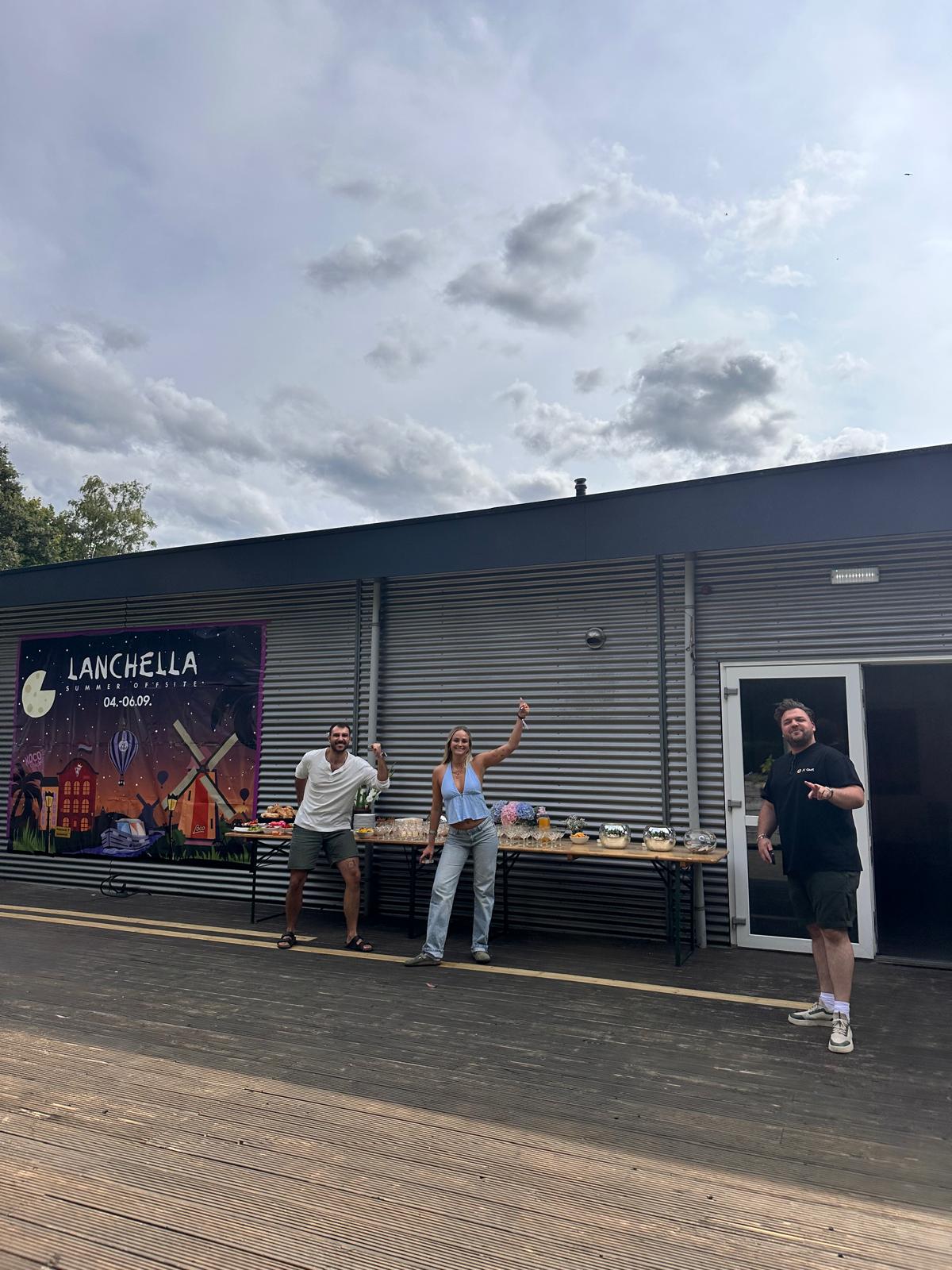 Colleagues celebrating in front of the Lanchella summer offsite banner